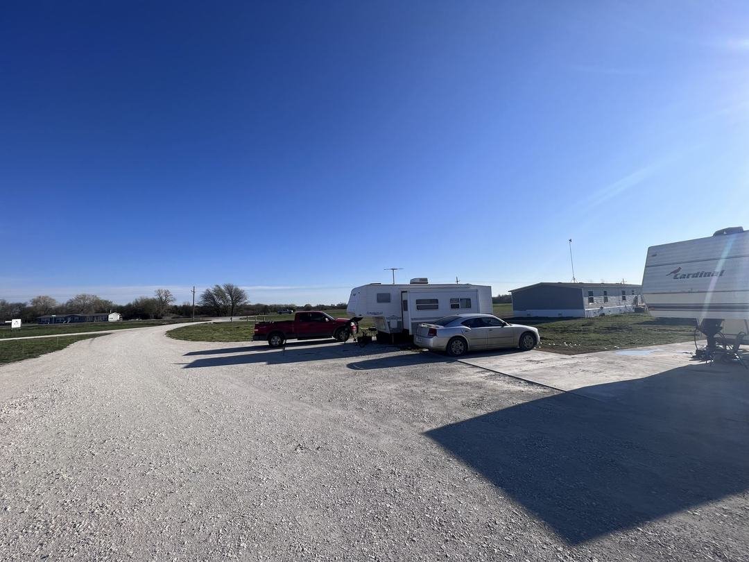 RV parked under a metal covered carport at a park site