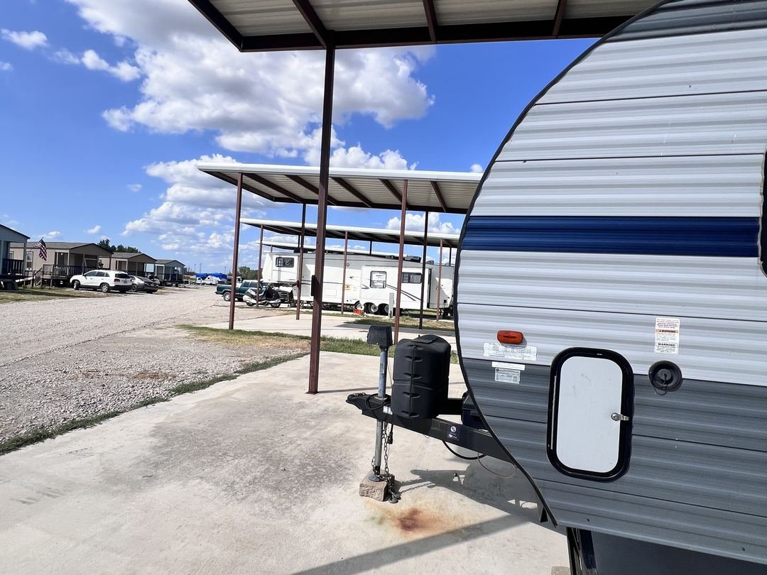 Travel trailer parked under a covered site carport
